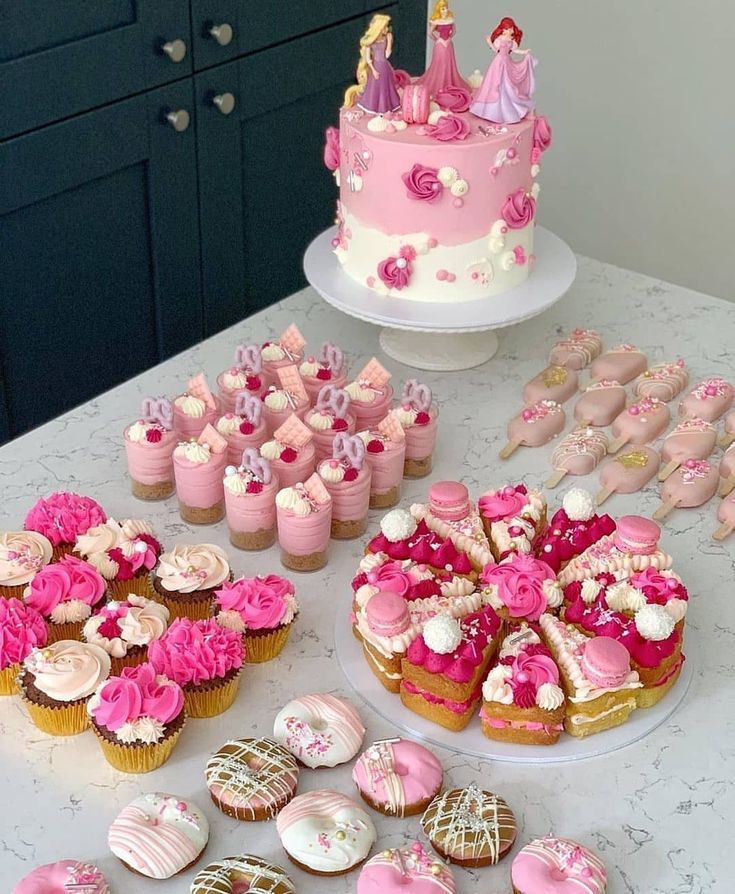 a table topped with lots of cupcakes and cakes