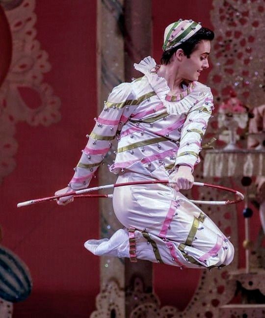 a man in white and pink striped outfit holding a pole while standing on top of a stage