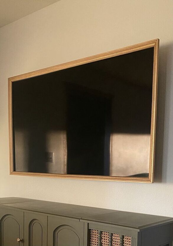 a tv mounted to the side of a white wall next to a dresser with drawers