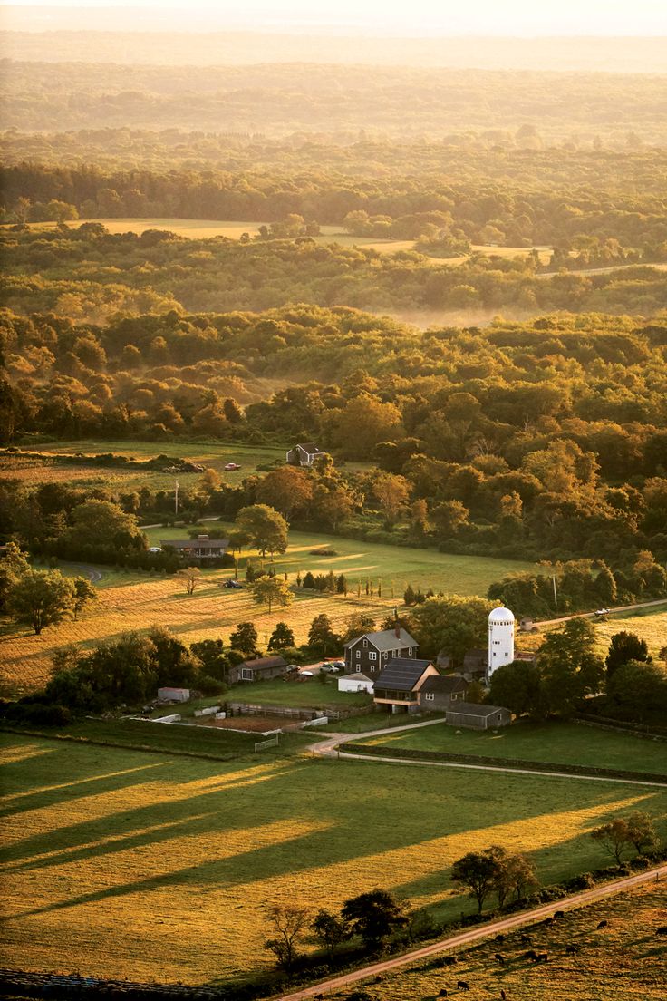 an aerial view of a farm with trees and fields in the foreground at sunset