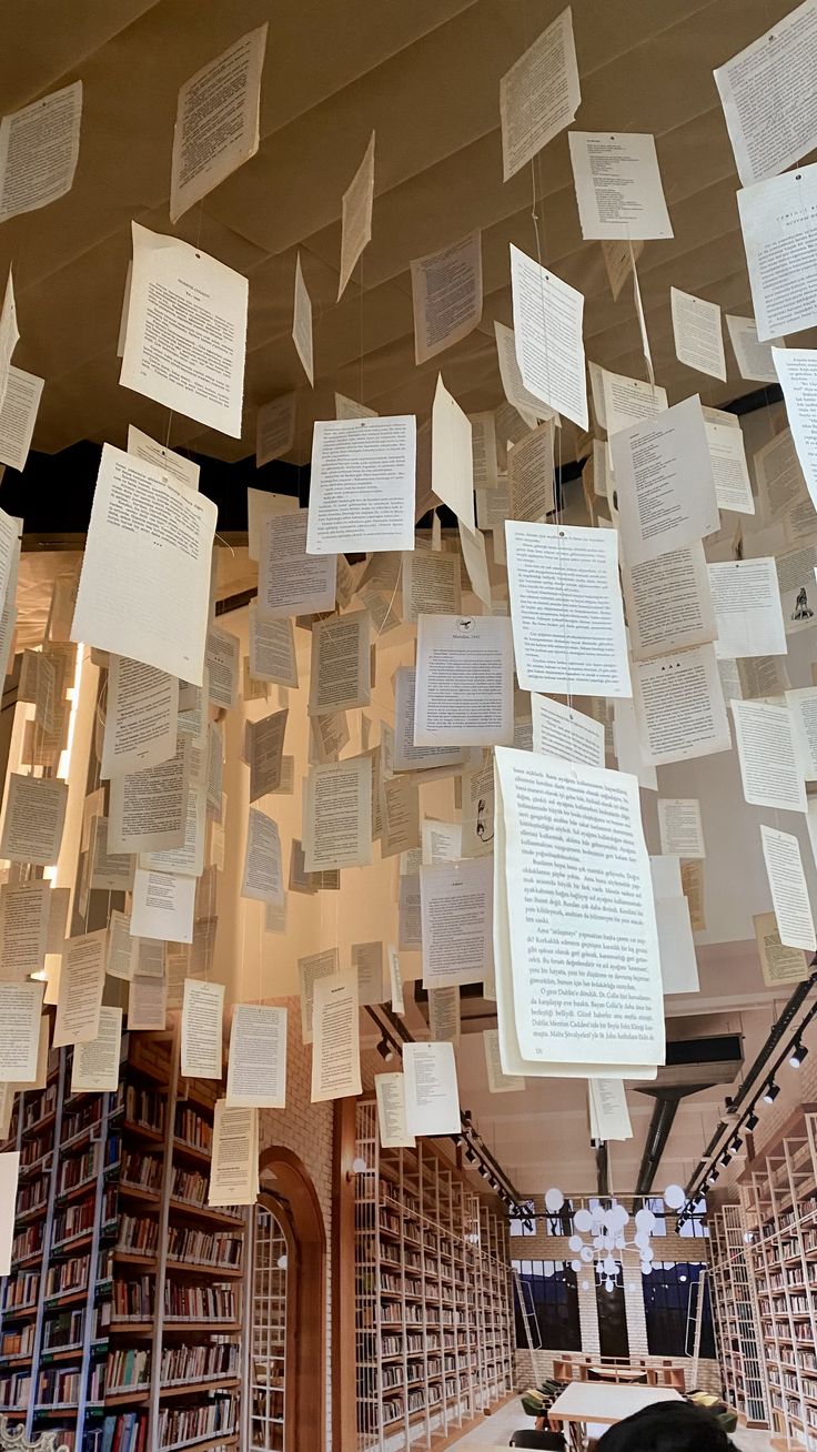 many books are hanging from the ceiling in a room with lots of paper on it