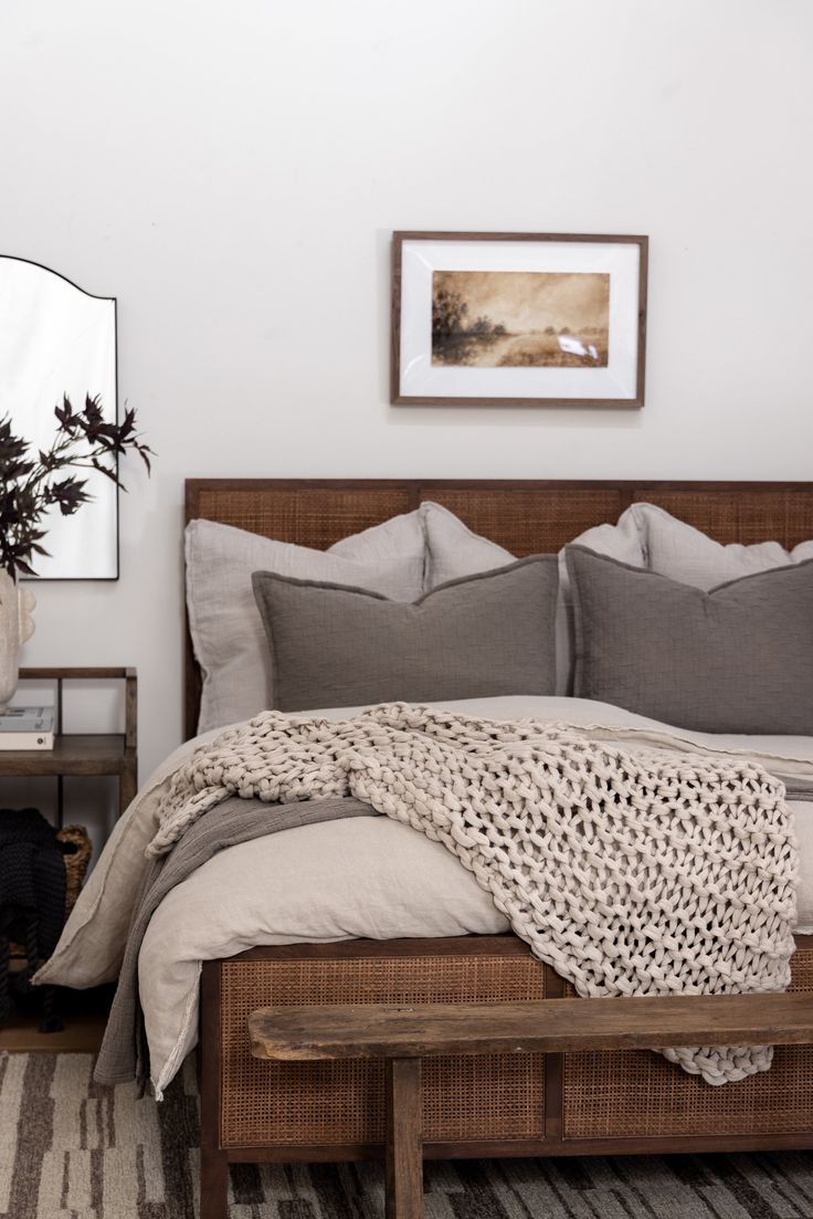 a bed sitting in a bedroom next to a mirror and table with a plant on it