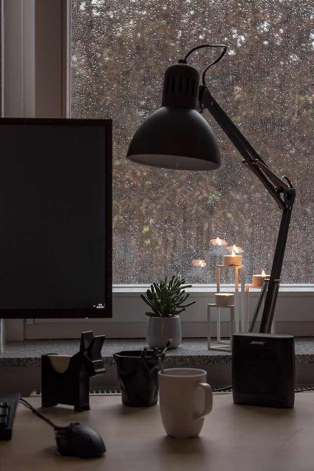 a desk with a monitor, keyboard and mouse on it next to a window covered in snow