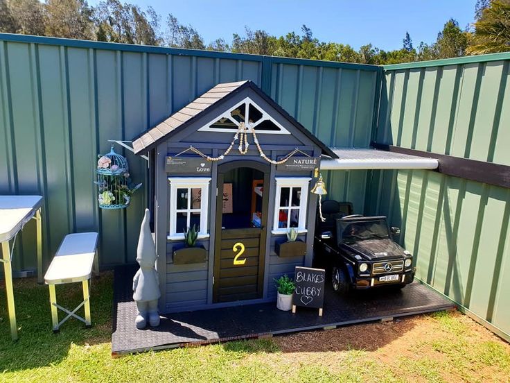 a car is parked in front of a small shed with a porch and awning