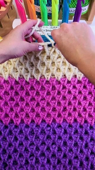 a person is knitting with crochet in front of colorful yarns and scissors