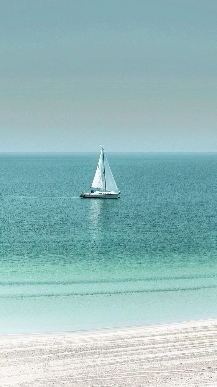 a sailboat is out on the open water near an empty beach with white sand