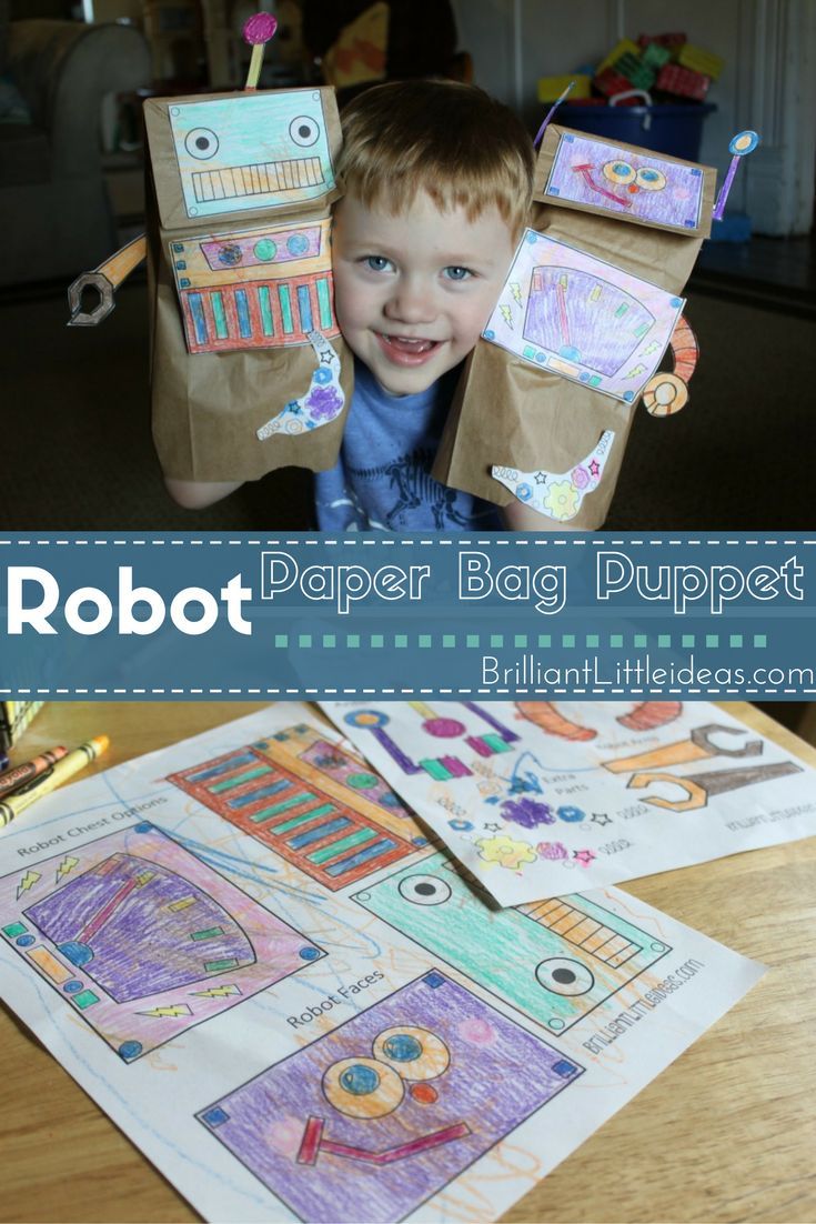 a young boy sitting at a table with paper bag puppets