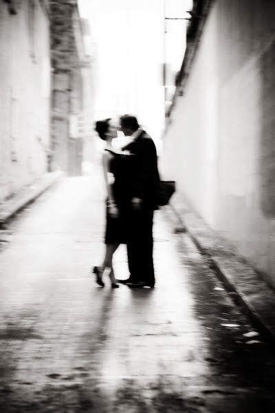 a man and woman kissing in an alley