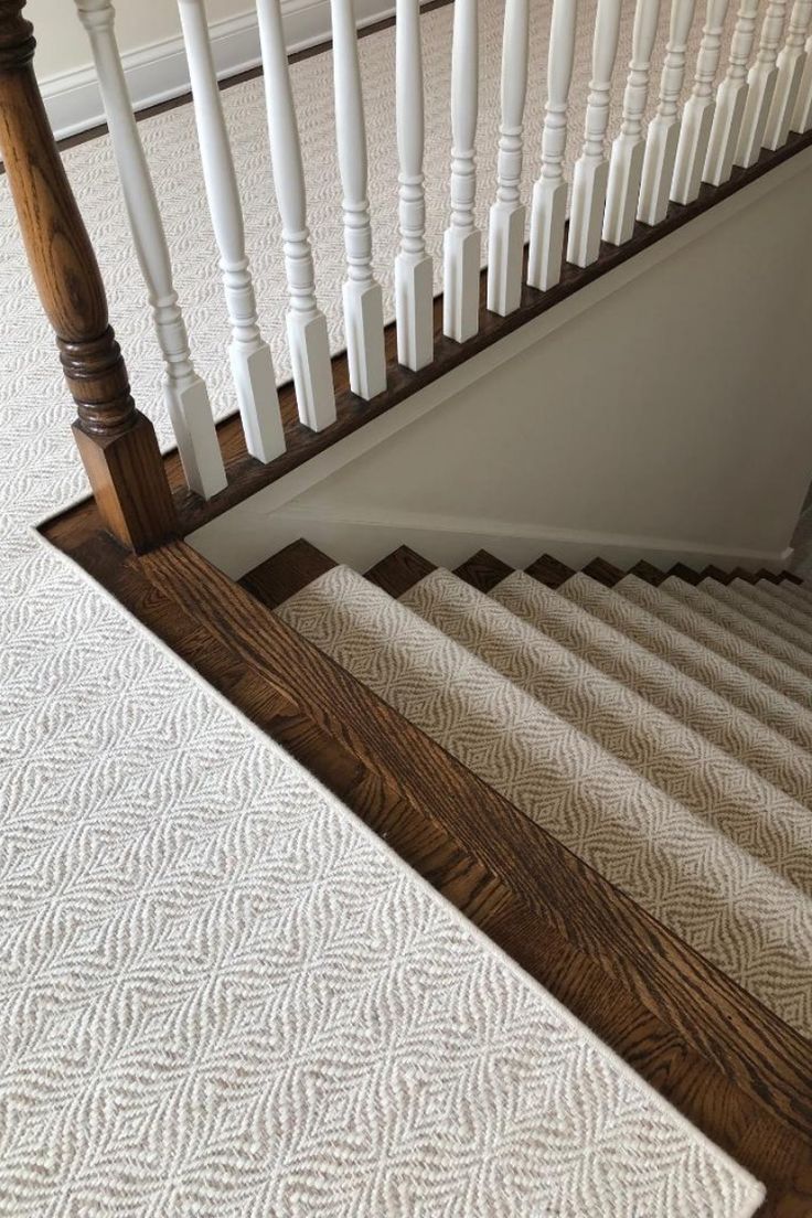 a stair case with white carpet and wooden handrails