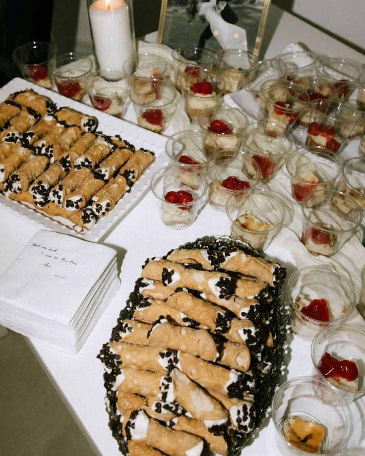 several desserts are displayed on a table with candles