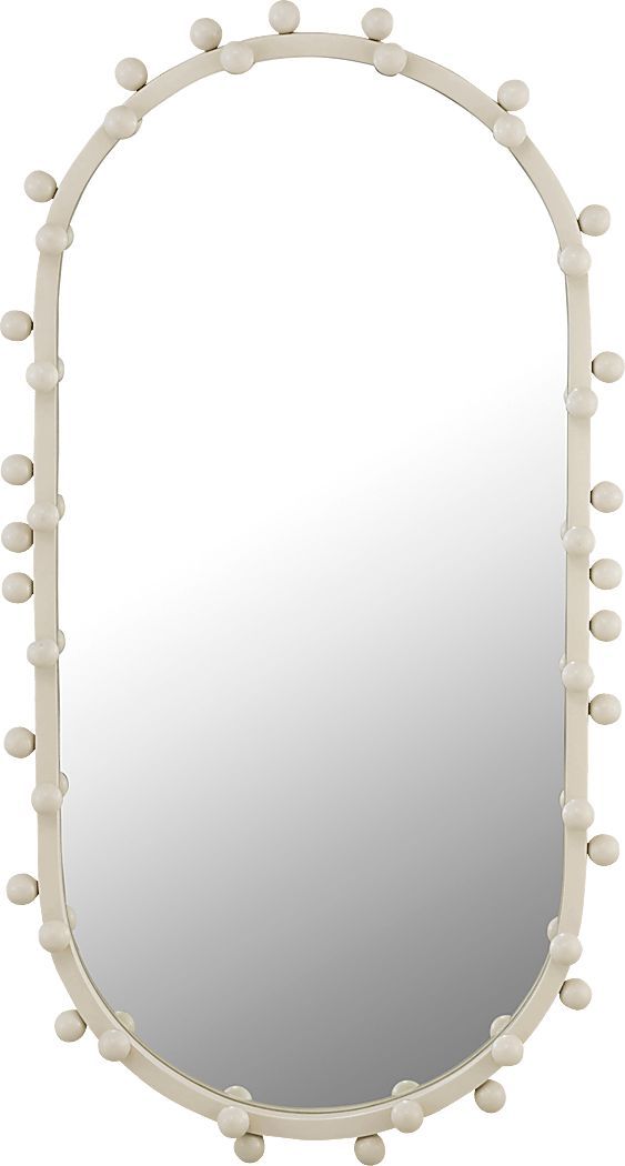 an oval mirror with white balls on the frame and bottom half covered in cream colored paint