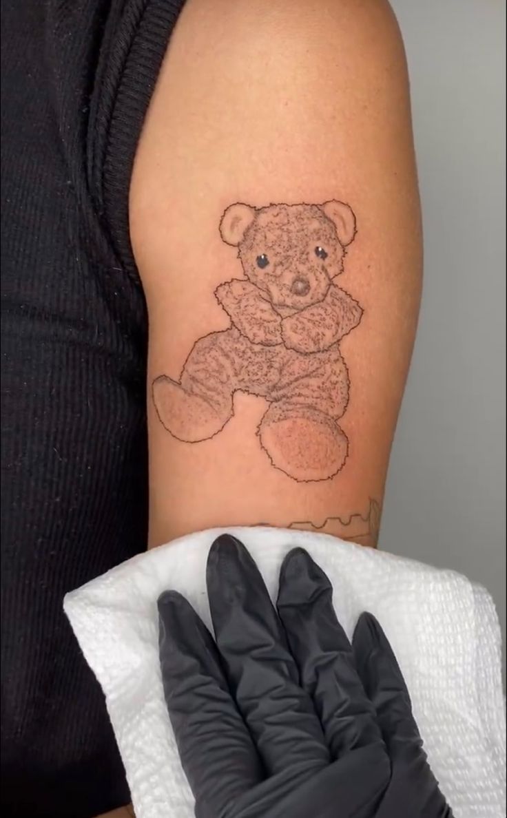 a woman's arm with a teddy bear tattoo on it