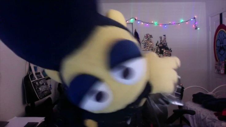 a yellow and black stuffed animal in a room with christmas lights on the wall behind it