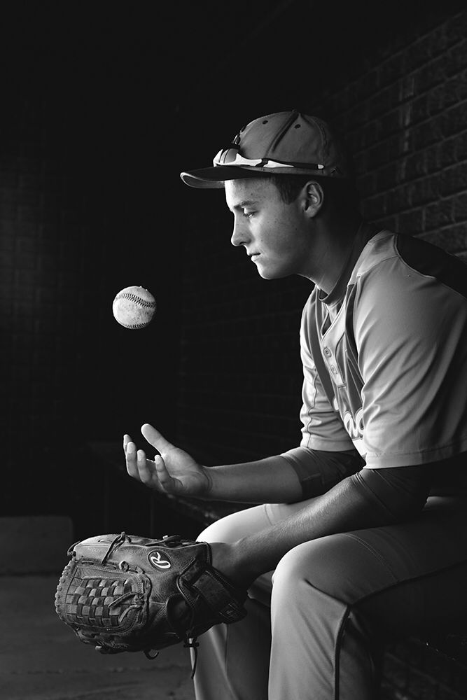 black and white photograph of a baseball player throwing a ball to another player sitting on a bench