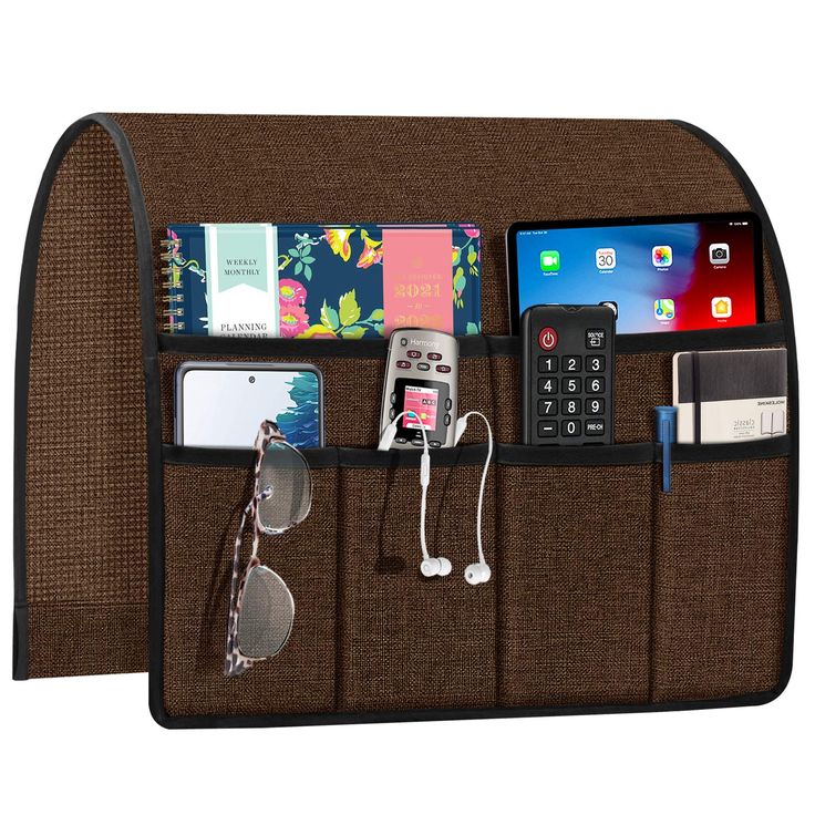 a cell phone and other items are hanging on the back of a wall pocket that is attached to a tabletop