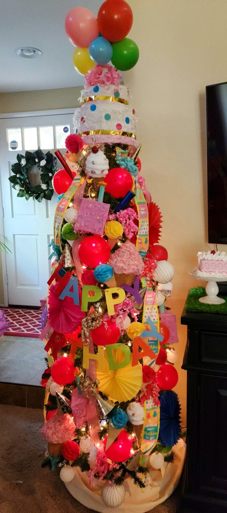 a decorated christmas tree with balloons and other items on the top, in a living room