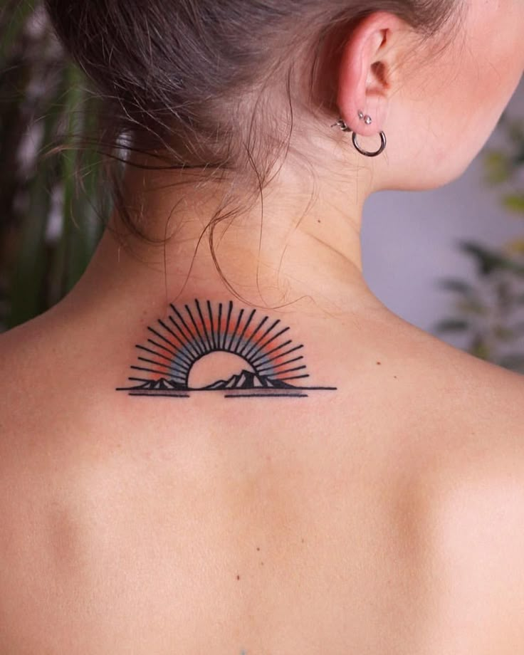 the back of a woman's neck with a sun tattoo on it