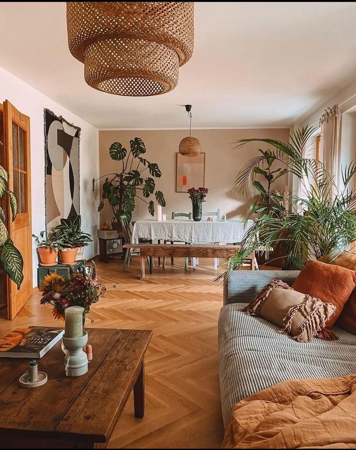 a living room filled with furniture and lots of plants on top of wooden flooring