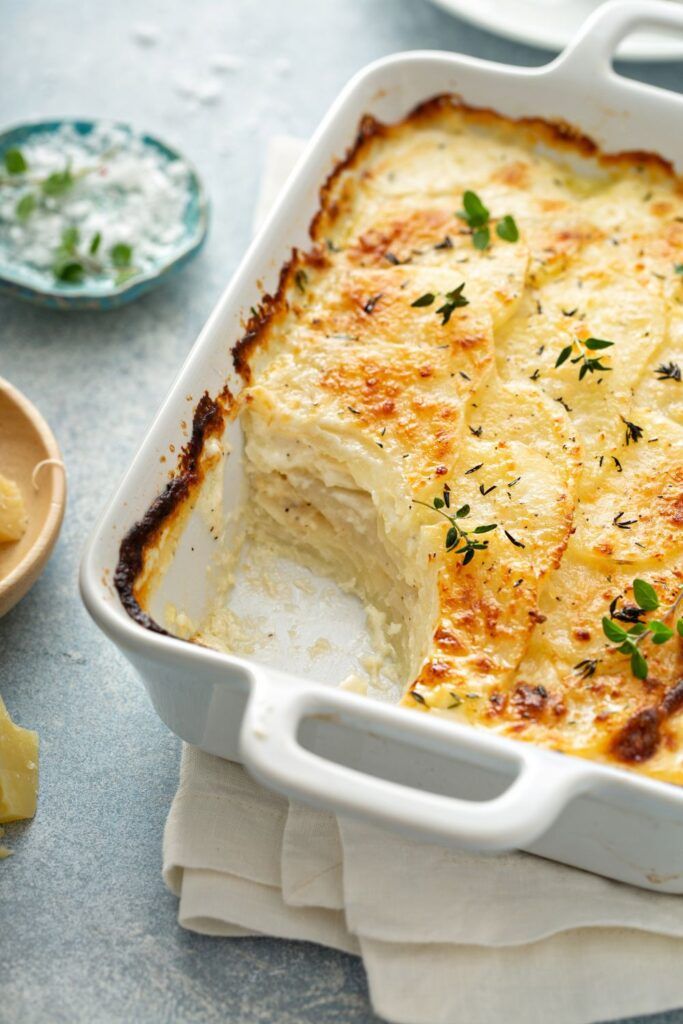 a casserole dish with cheese and herbs in it on a table next to other dishes