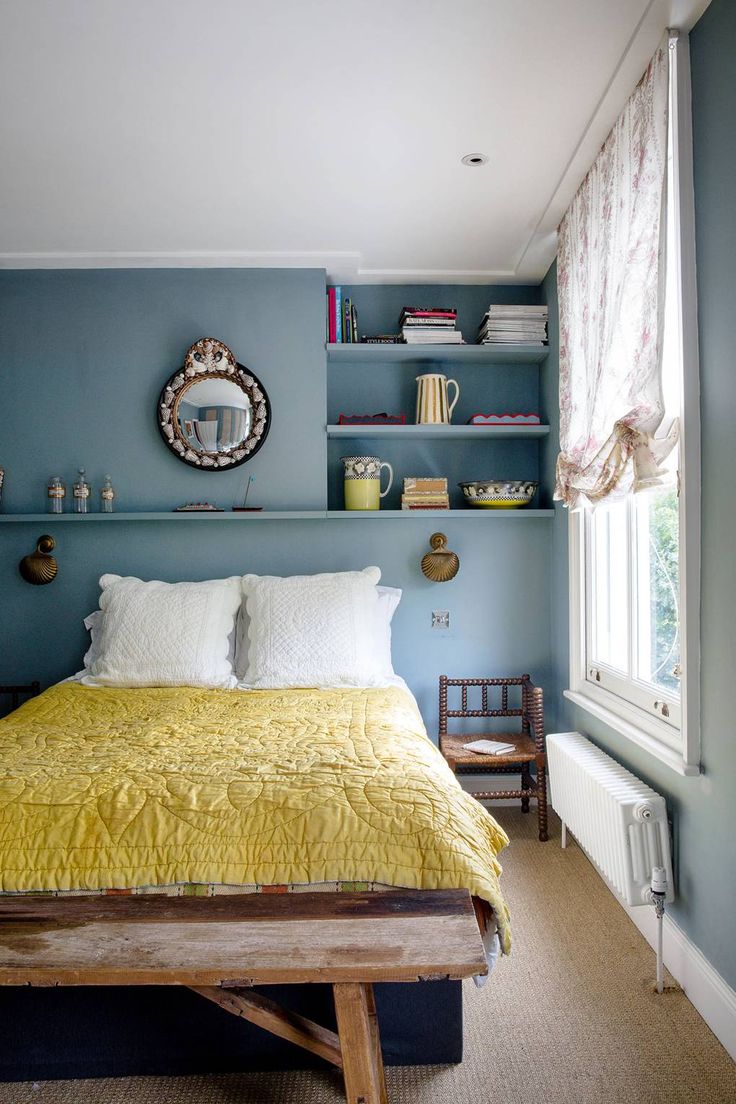 a bedroom with blue walls and yellow bedspread on a wooden platform in front of a window