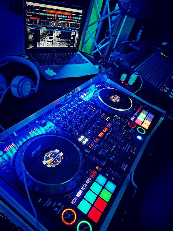 a laptop computer sitting on top of a desk next to a dj's turntable