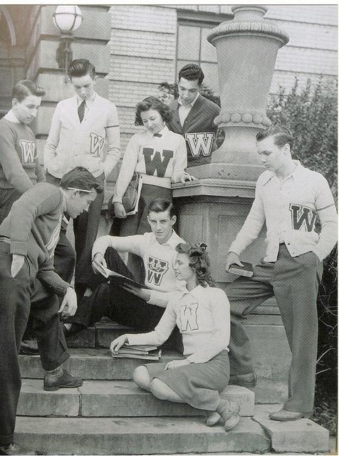 a group of young men and women sitting on steps next to each other in front of a building