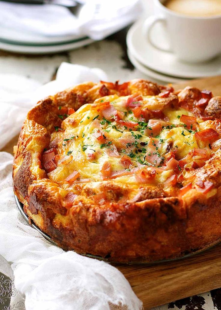 a pizza sitting on top of a wooden cutting board next to a cup of coffee