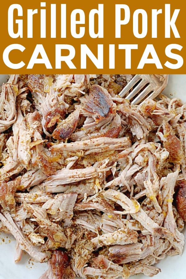 pulled pork carnitas on a white plate with a fork and text overlay that reads grilled pork carnitas