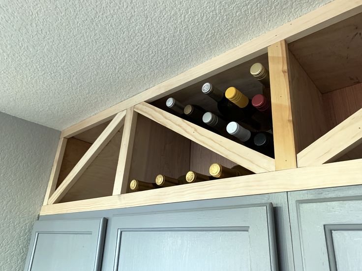 a wine rack in the corner of a kitchen with gray cupboards and white walls