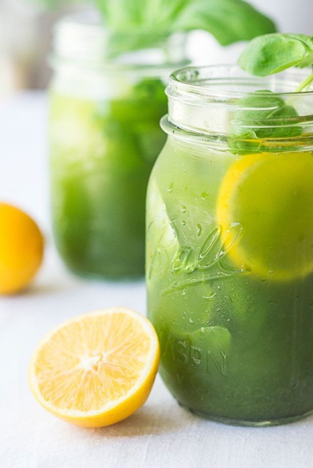 two mason jars filled with lemonade, basil and lime slices next to each other