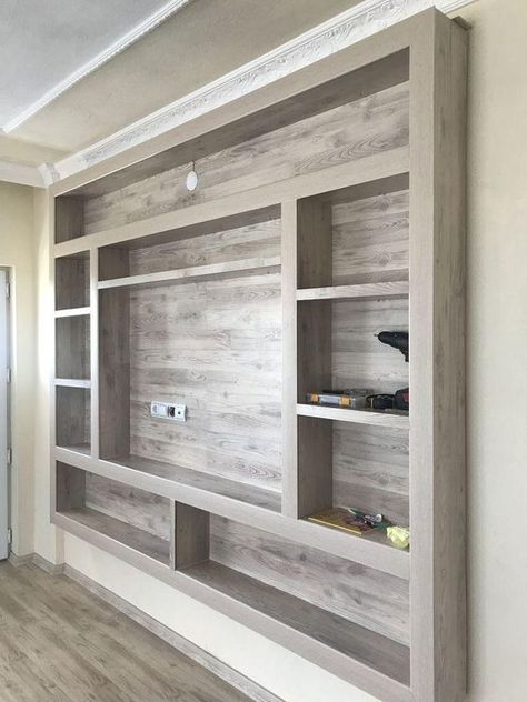 an empty living room with wooden shelves on the wall and wood flooring in front of it