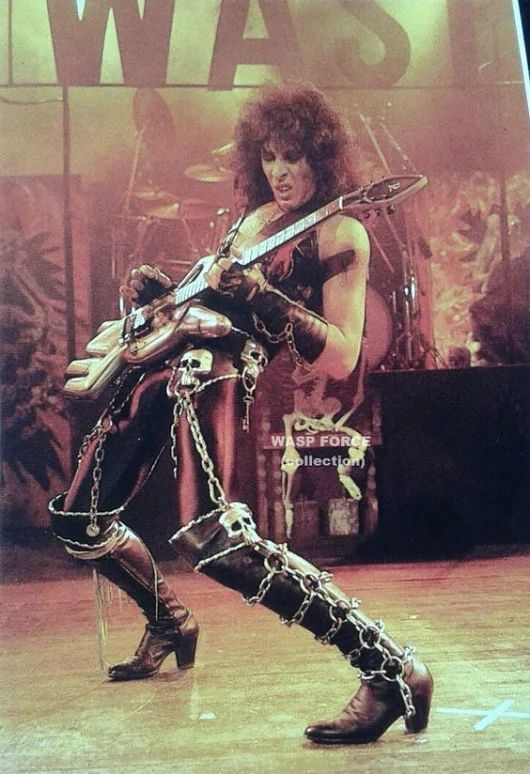 a woman in chains and boots holding a guitar