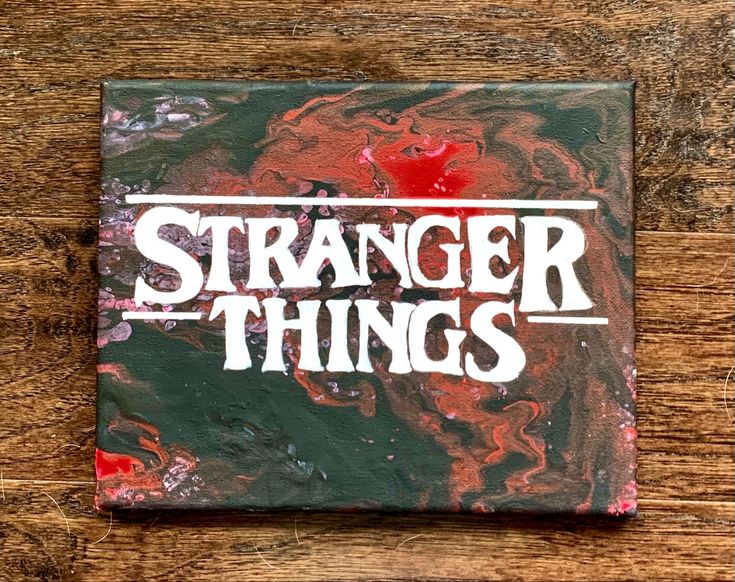 a square coaster with the words,'strange things'painted on it