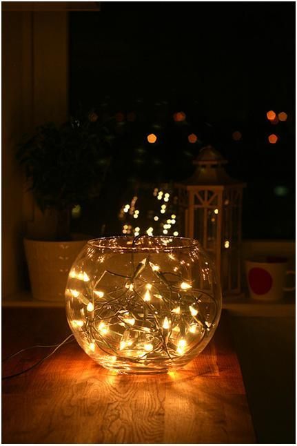 a glass bowl filled with lights on top of a wooden table