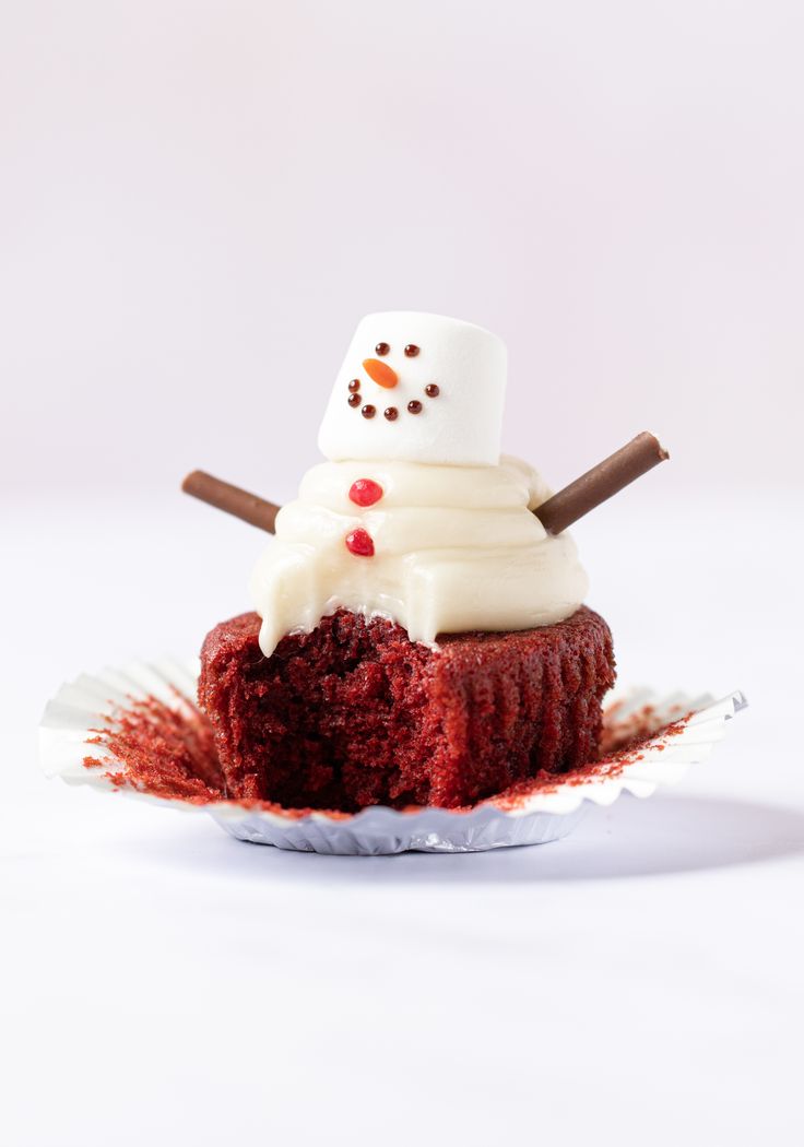 a cupcake with frosting and a snowman on top