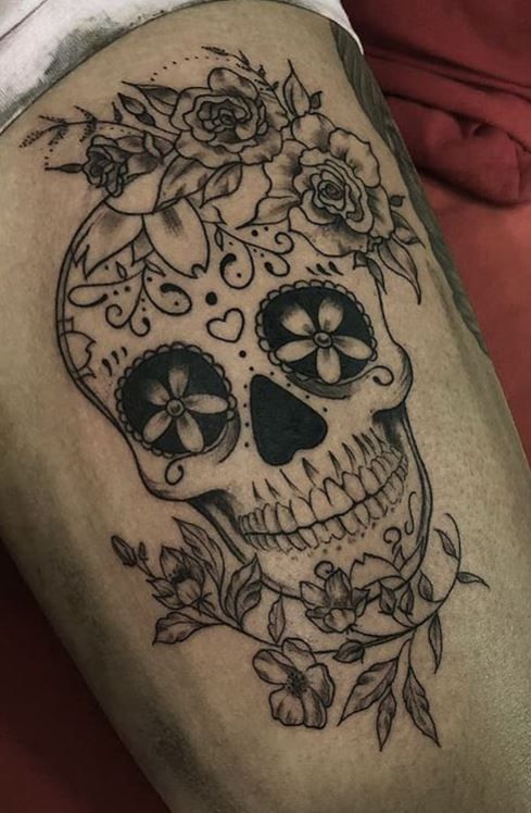 a woman's thigh with a skull and roses tattoo on it