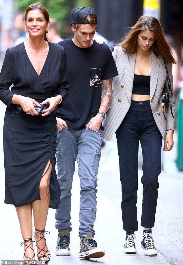 a man and woman walking down the street with one holding her hand behind her back