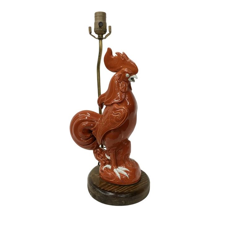 a figurine of a rooster holding a flower in its beak, on a wooden base