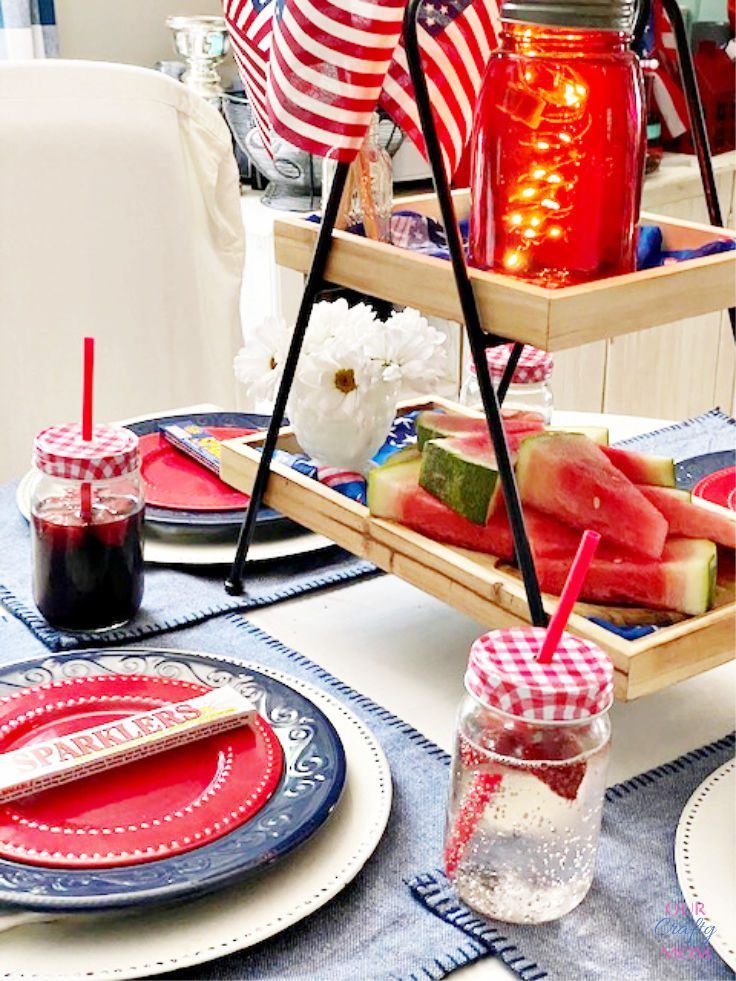 a patriotic table setting with red, white and blue plates and glasses filled with watermelon slices