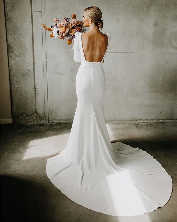 a woman in a white dress holding flowers and looking at the back of her dress