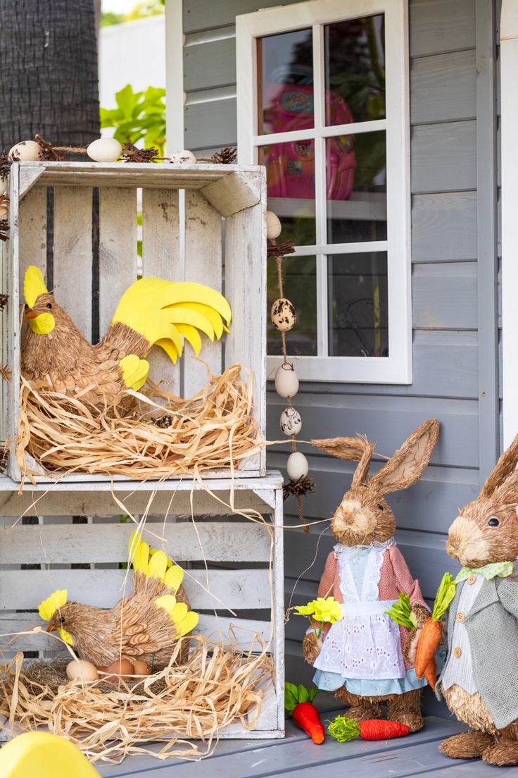 three wooden crates filled with fake rabbits sitting on top of a porch next to a house