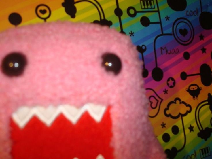 a close up of a stuffed animal with its mouth open and teeth wide open on a colorful background