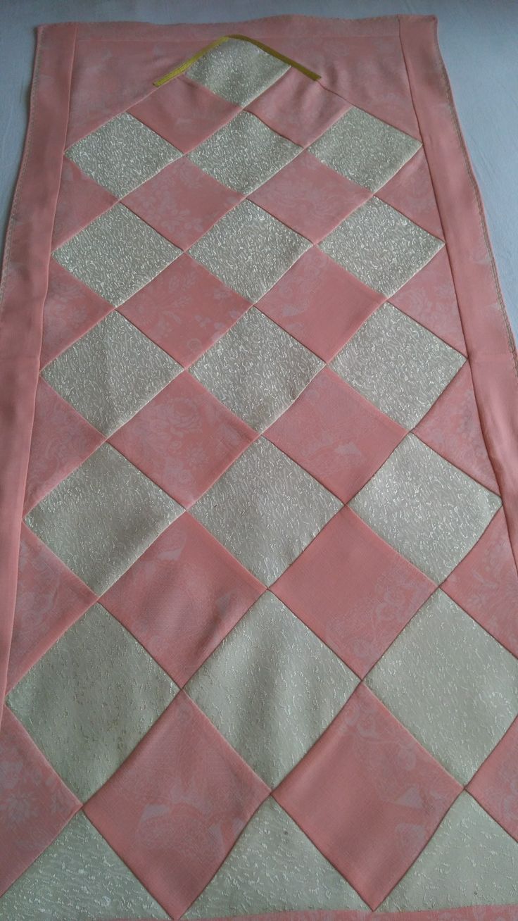 a pink and beige quilted blanket laying on top of a table