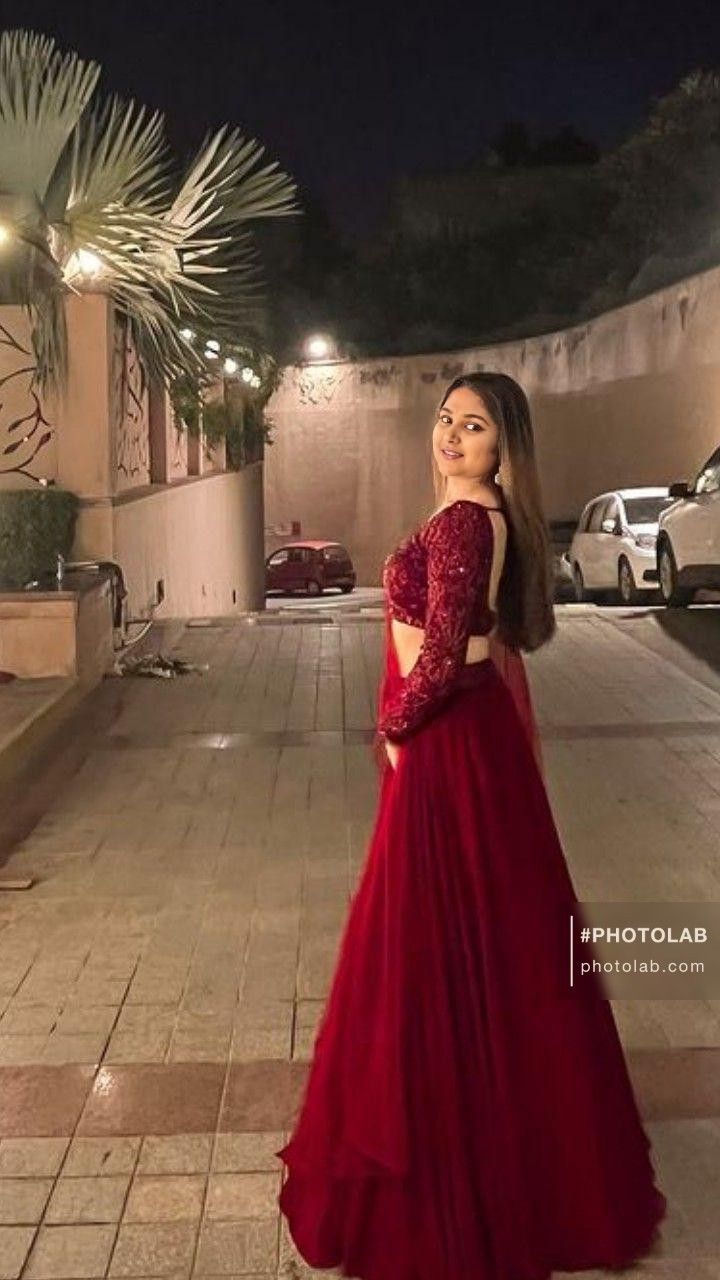 a woman in a red dress standing on the sidewalk with her back to the camera