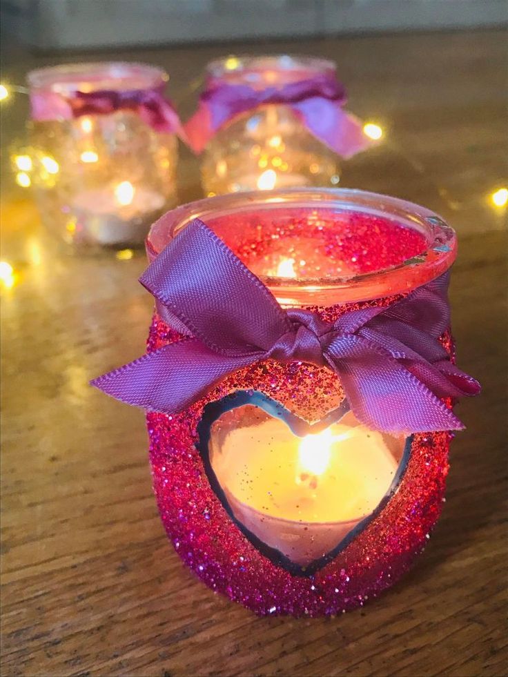 some candles are sitting on a table with lights around them and one has a heart shaped candle in the center