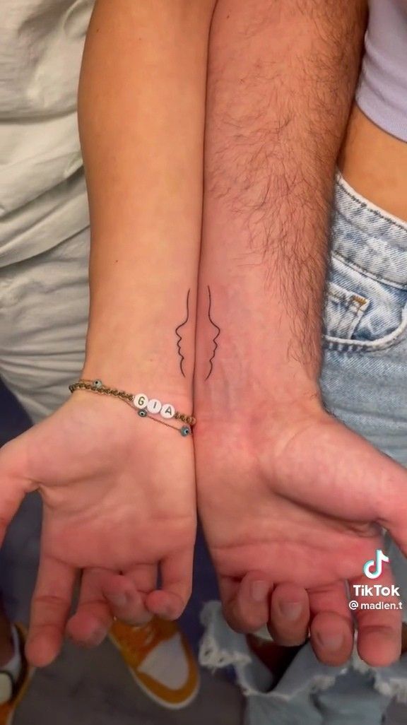 two people holding hands with tattoos on them