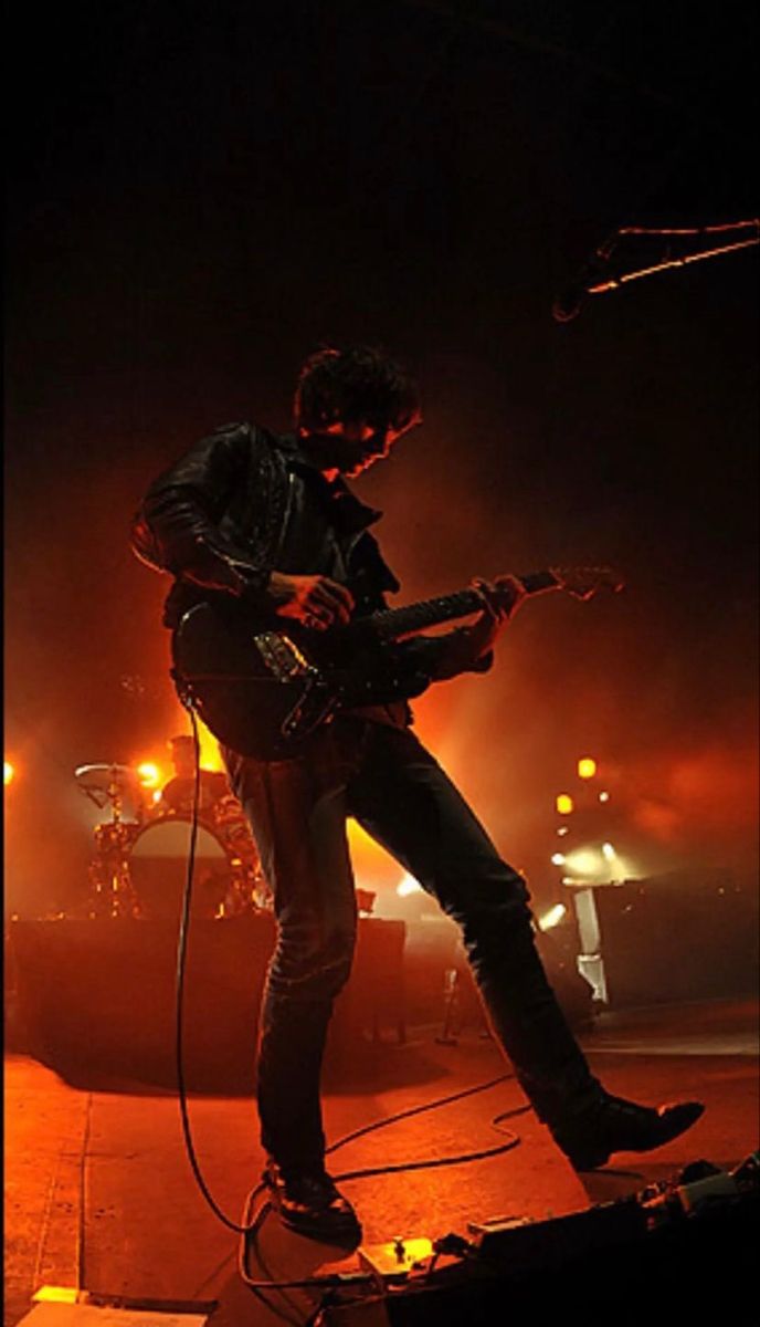 a man playing an electric guitar in front of a microphone and stage lights at night