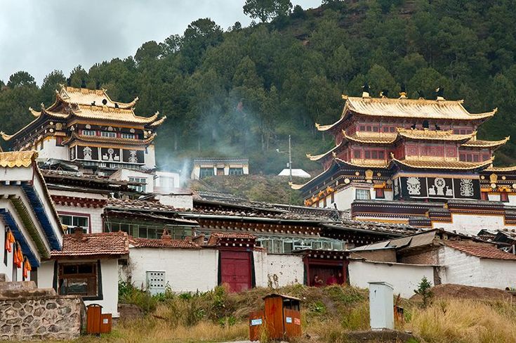 an old chinese village with mountains in the back ground and trees on the other side