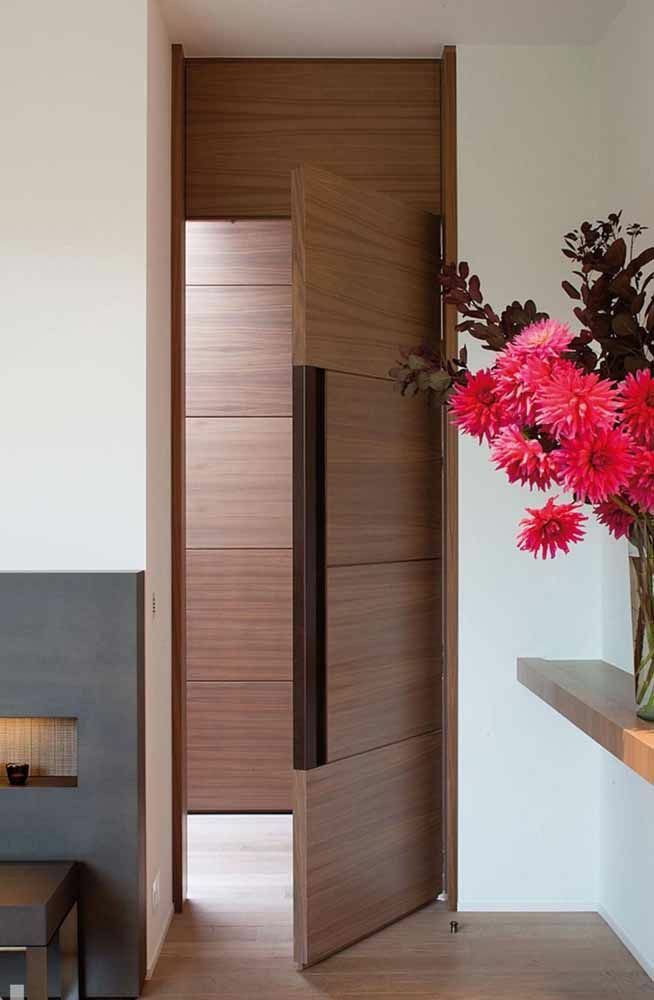 a vase filled with red flowers sitting on top of a wooden table next to a fireplace