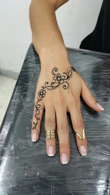 a woman's hand with a henna tattoo on her left wrist and fingers